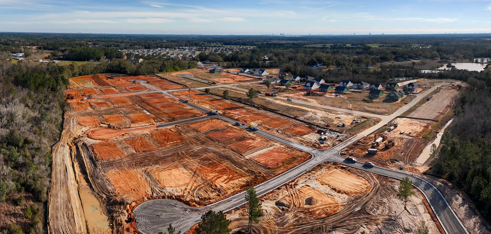 Wide aerial of an orange-dirt land development site under construction in Baldwin County, Alabama